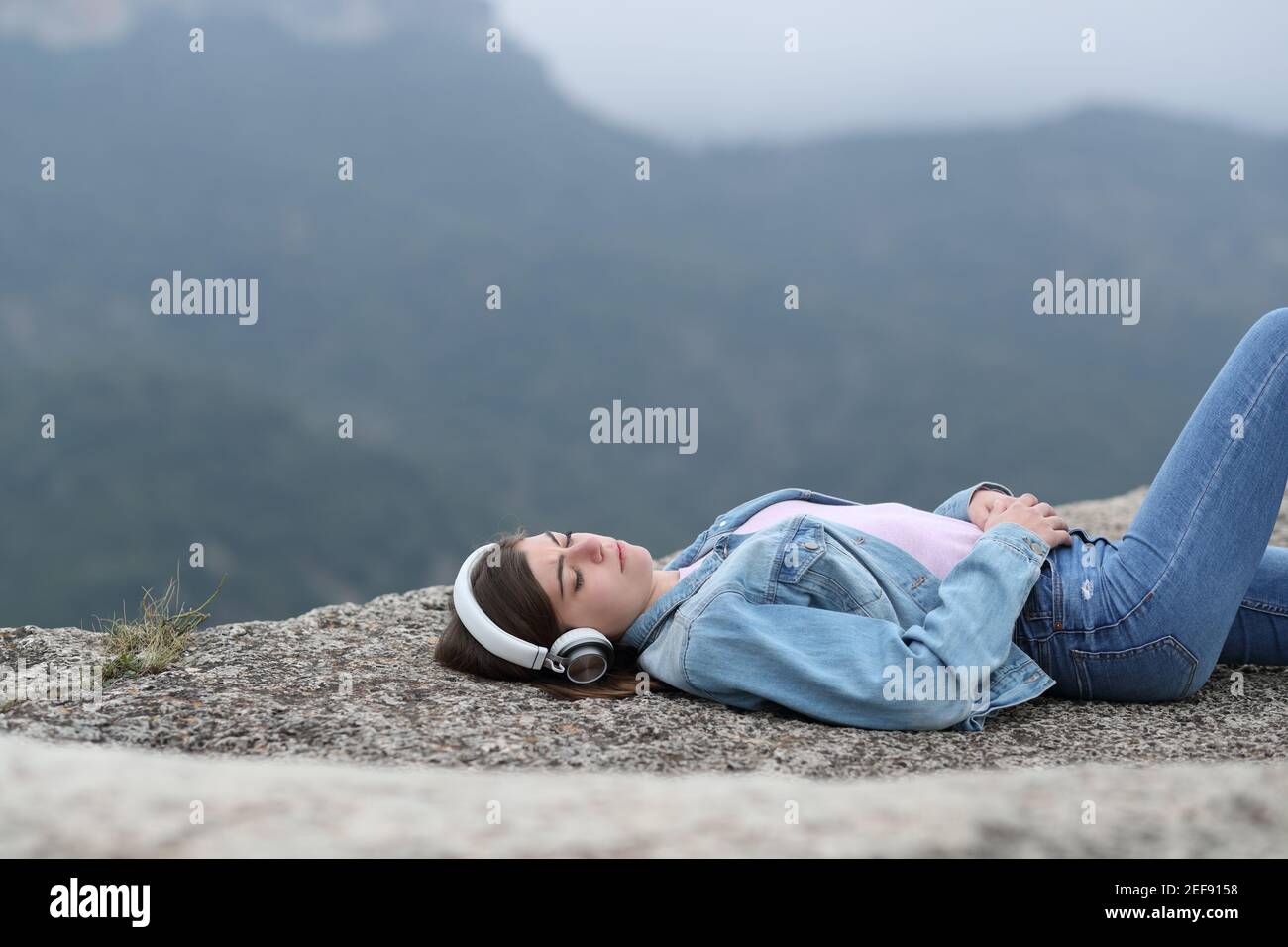 Traurige Teenager, die Musik tragen Kopfhörer allein in der hören Berg Stockfoto