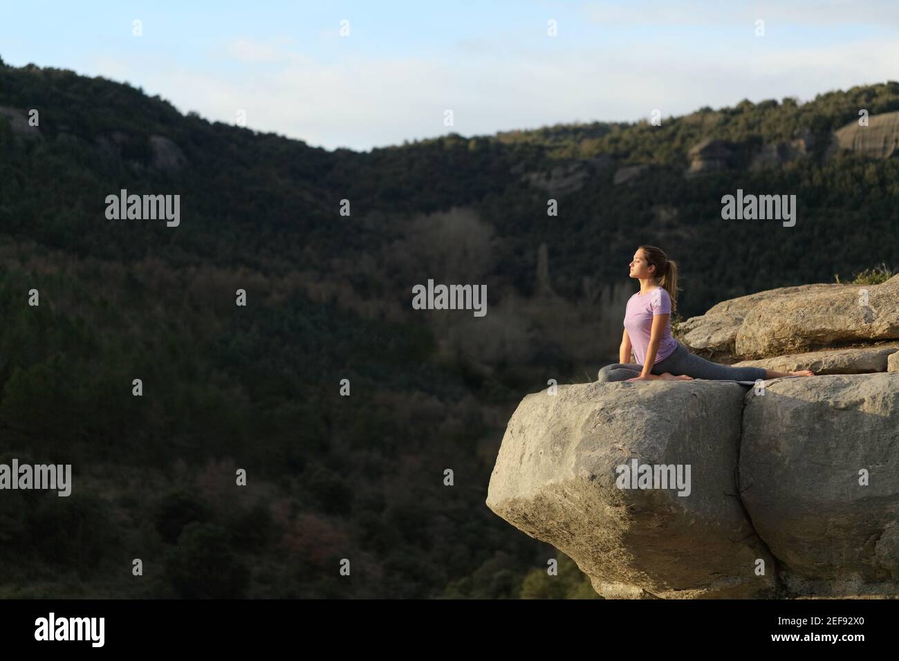 Konzentrierter Yogi, der Yoga-Übung oben auf einem praktiziert Klippe in den Bergen Stockfoto