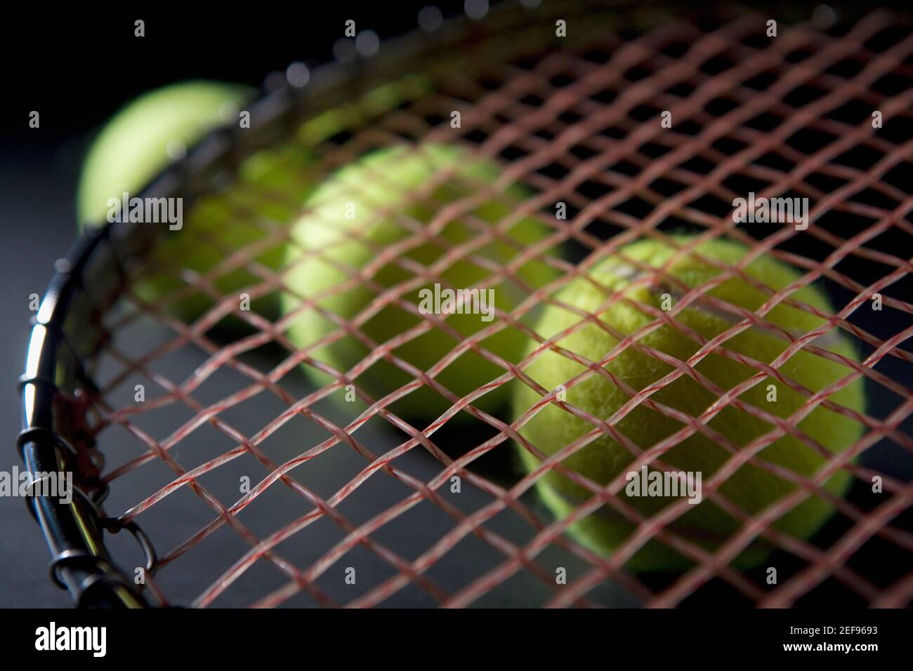 Nahaufnahme eines Tennisschlägers mit drei Tennisbällen Stockfoto