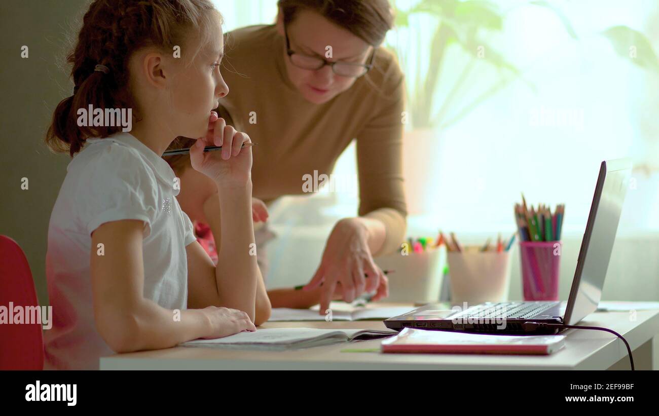 Nette Kinder verwenden Laptop für Bildung, Online-Studie, zu Hause studieren, Junge und Mädchen haben Hausaufgaben auf Distanz lernen. Lifestyle-Konzept für Home Schooling. Mutter hilft Tochter und Sohn. Stockfoto