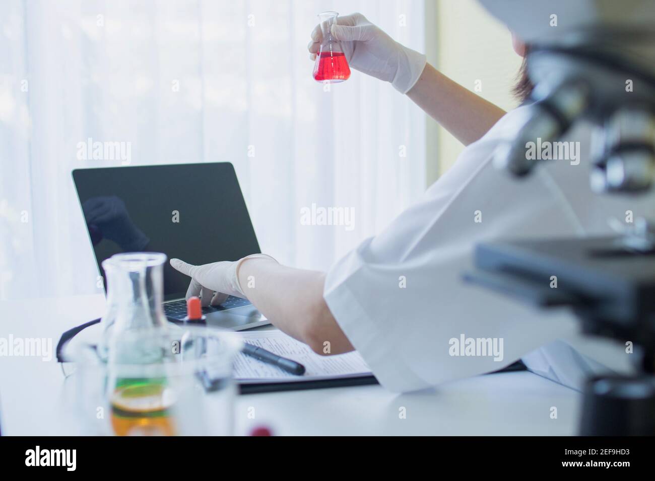 Laborwissenschaftler in einem Overall, der Forschung durchführt. Chemiker oder Arzt Forschung und Test antiretrovirale Medikamente und finden Sie Informationen auf Laptop , ho Stockfoto