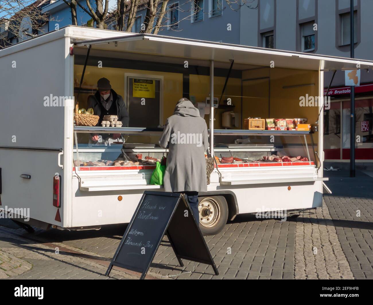 NEUWIED, DEUTSCHLAND - 10. Feb 2021: Neuwied, Deutschland - 12. Februar 2021: Ein Marktstand mit einem Kunden in der Fußgängerzone Stockfoto