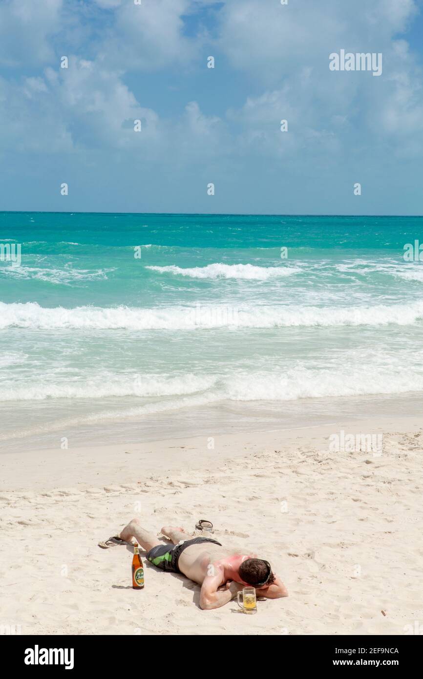 Ein Backpacker schläft am Strand mit Eisbier und Sonnenbrand, Haad Rin (aka Sunrise) Party Beach & Site der Full Moon Party, Ko Phangan, Thailand Stockfoto