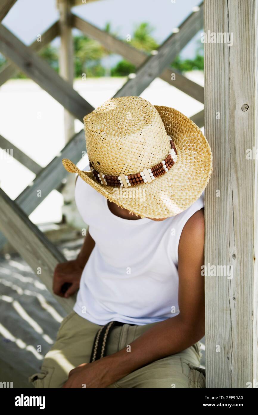 Aus der Perspektive eines jungen Mannes, der einen Strohhalm trägt hut und sitzen unter einem Pier Stockfoto