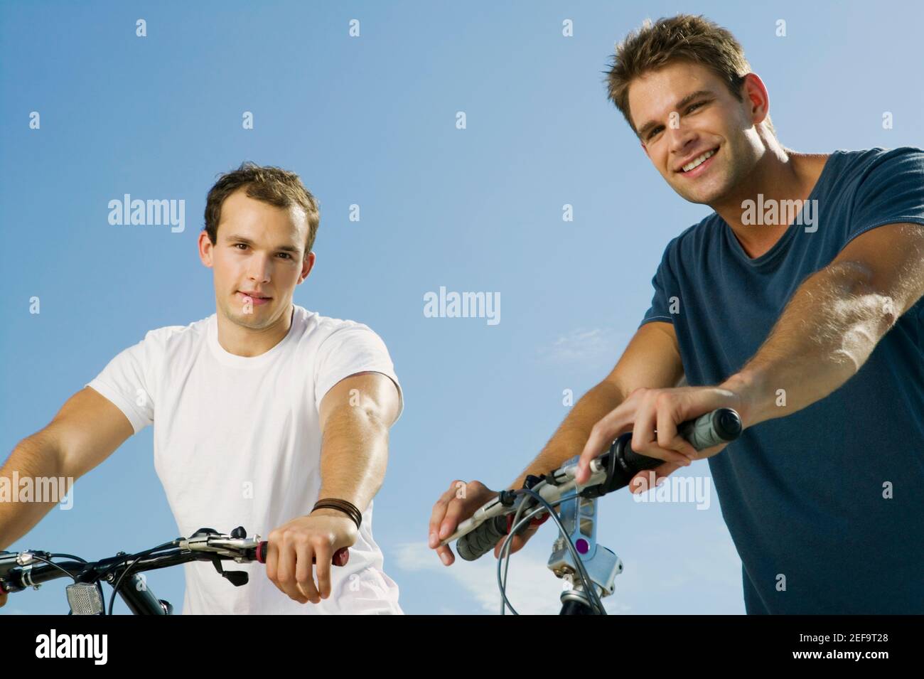 Porträt zweier junger Männer, die lächeln und Fahrräder halten Stockfoto