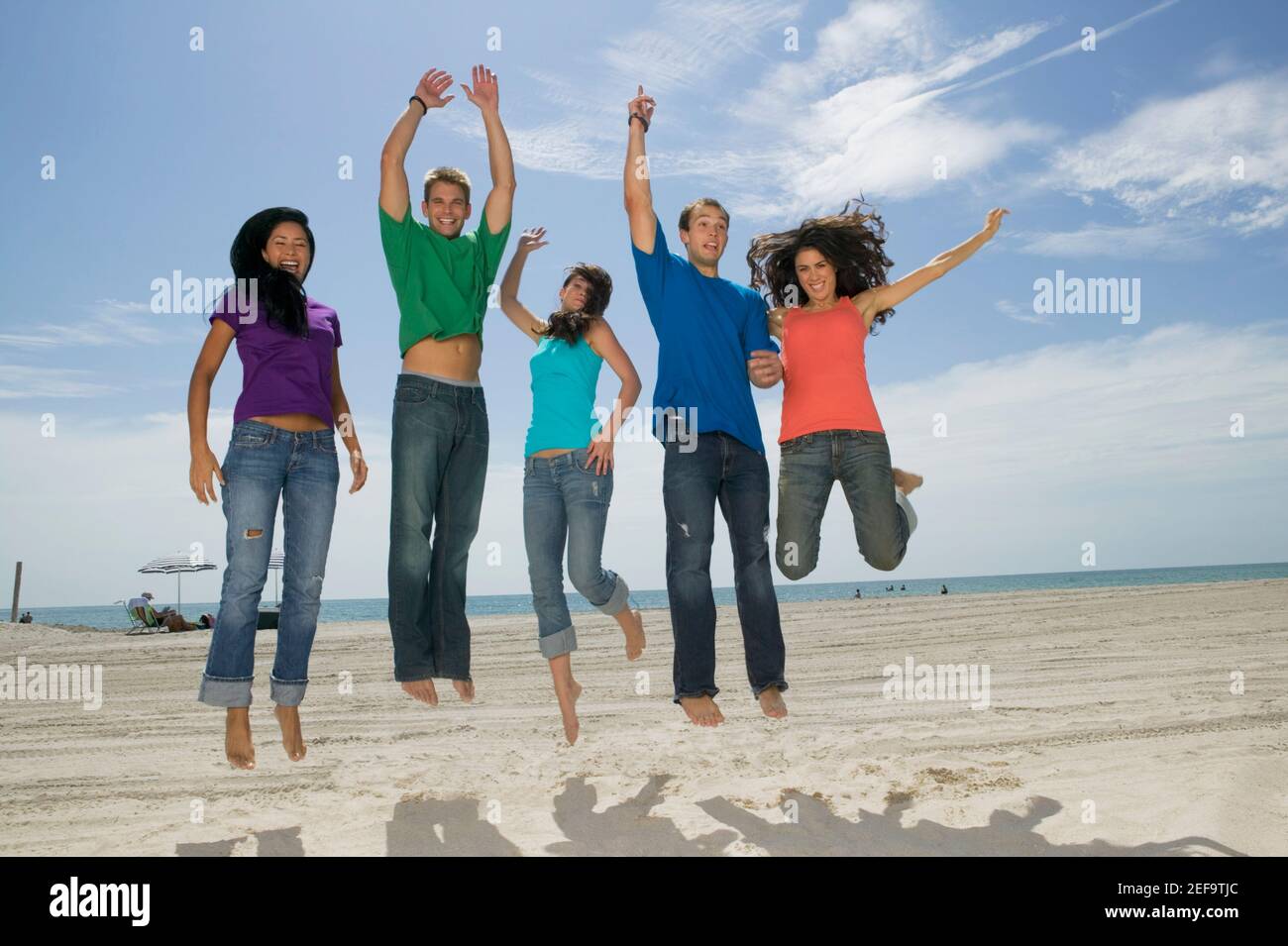 Low-Angle-Ansicht von drei jungen Frauen und zwei jungen Männer springen am Strand Stockfoto