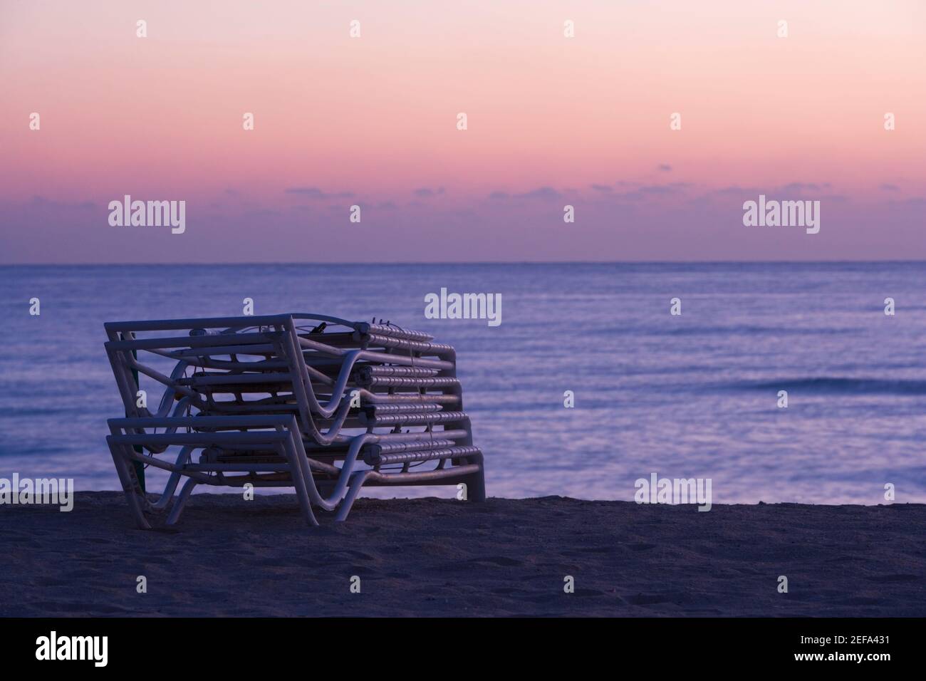 Stapel von gefalteten Liegestühlen am Strand, South Beach, Miami, Florida, USA Stockfoto