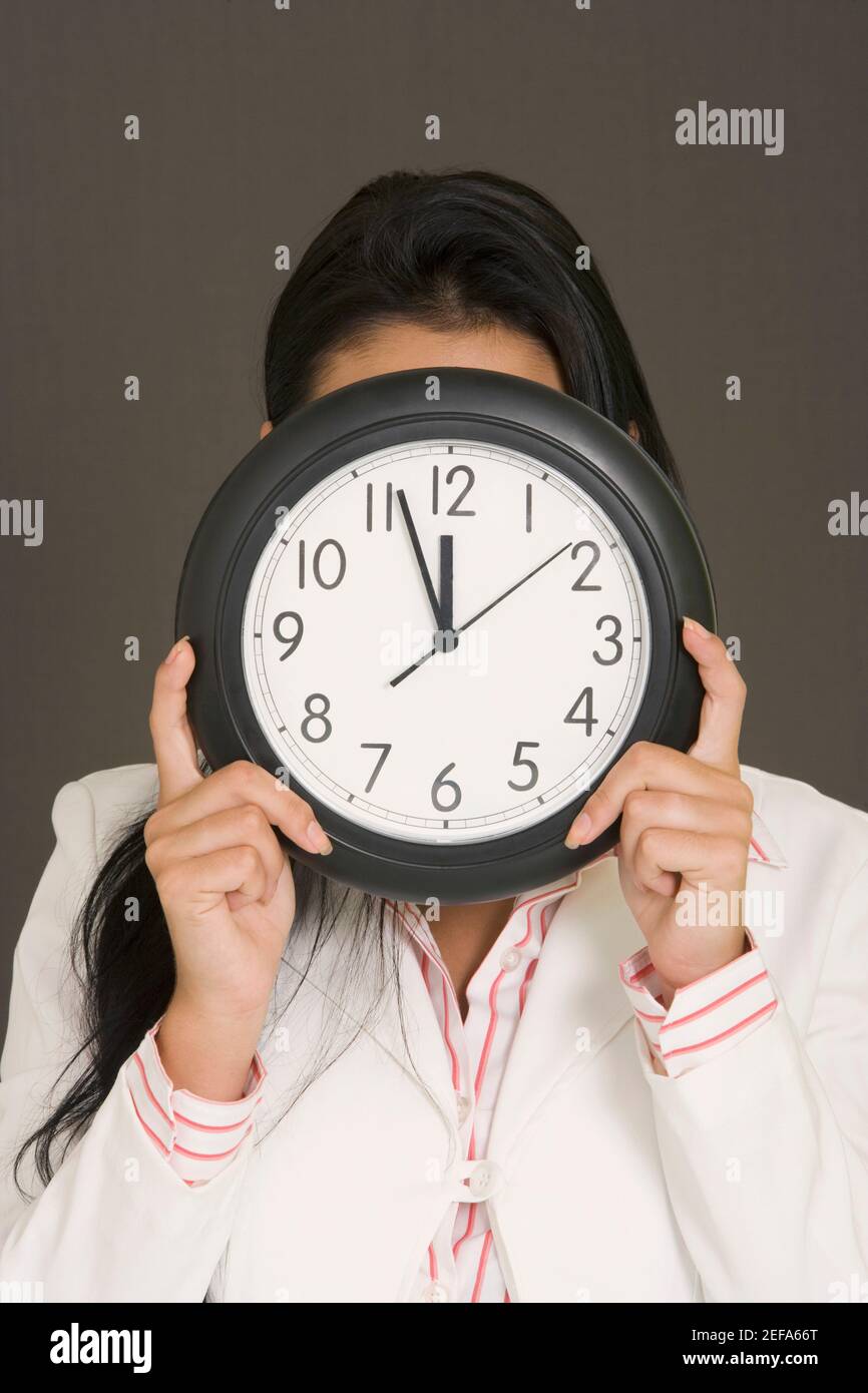 Nahaufnahme einer Geschäftsfrau, die ihr Gesicht mit einer Uhr versteckt Stockfoto