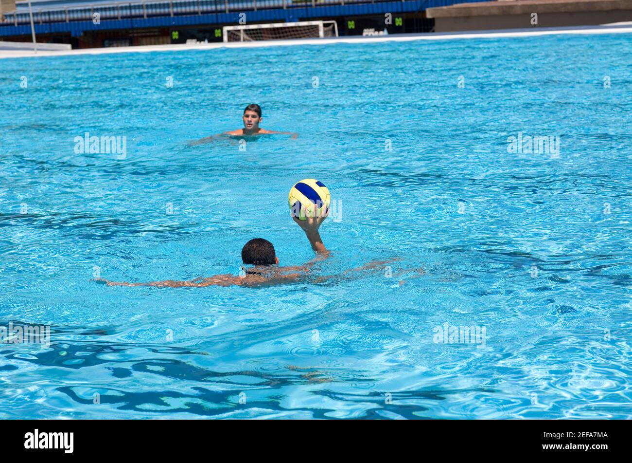 Zwei junge Männer spielen Wasserball in einem Schwimmbad Stockfoto