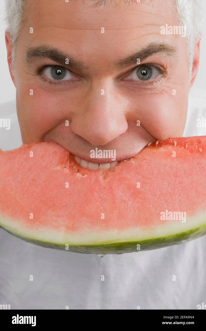 Porträt eines reifen Mannes, der eine Scheibe Wassermelone isst Stockfoto