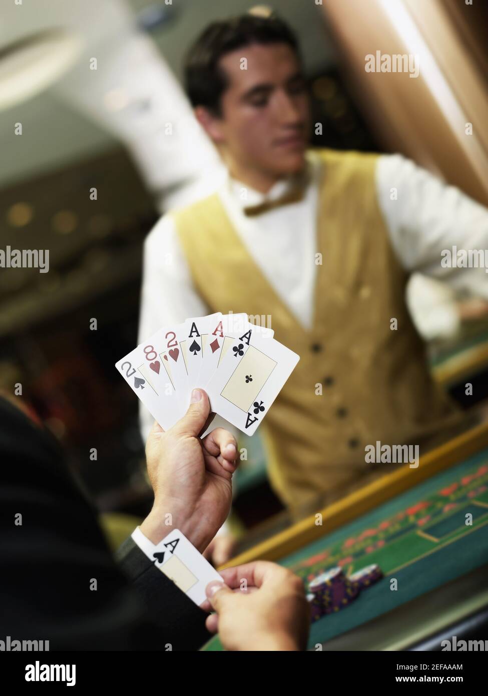 Junger Mann, der Spielkarten hält und ein Ass versteckt Seine Manschette Stockfoto