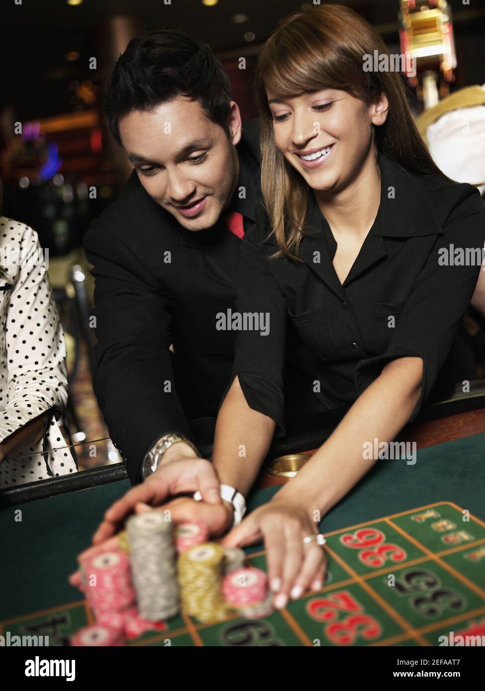 Mittelerwachsener Mann mit einer jungen Frau, die Spielchips platziert Auf einem Spieltisch Stockfoto
