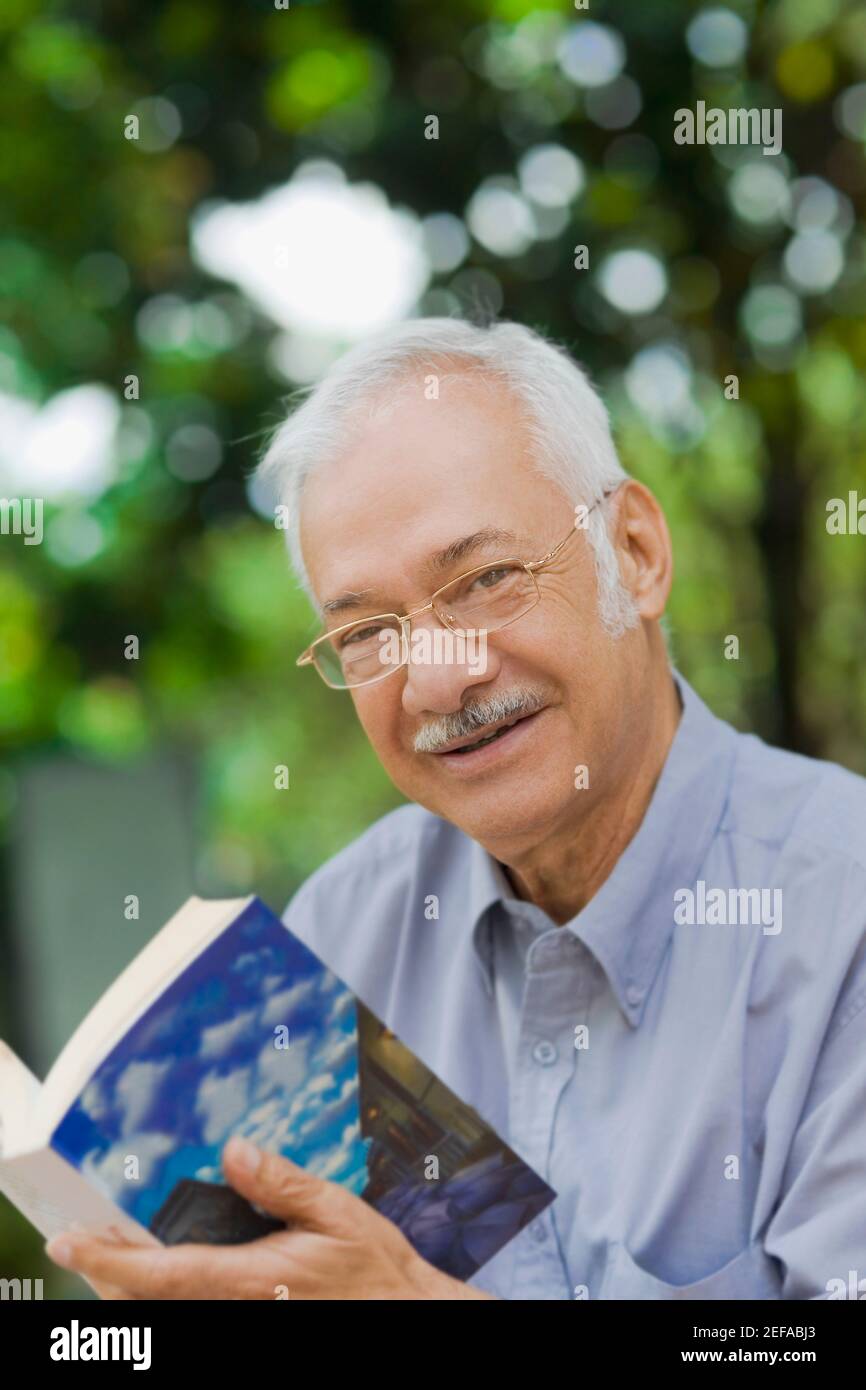 Porträt eines senior, der ein Buch hält und lächelnd Stockfoto
