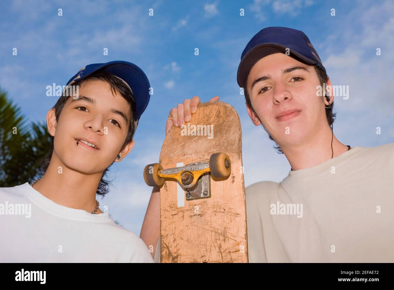 Portrait von zwei jungen Männern, die mit einem Skateboard stehen Stockfoto