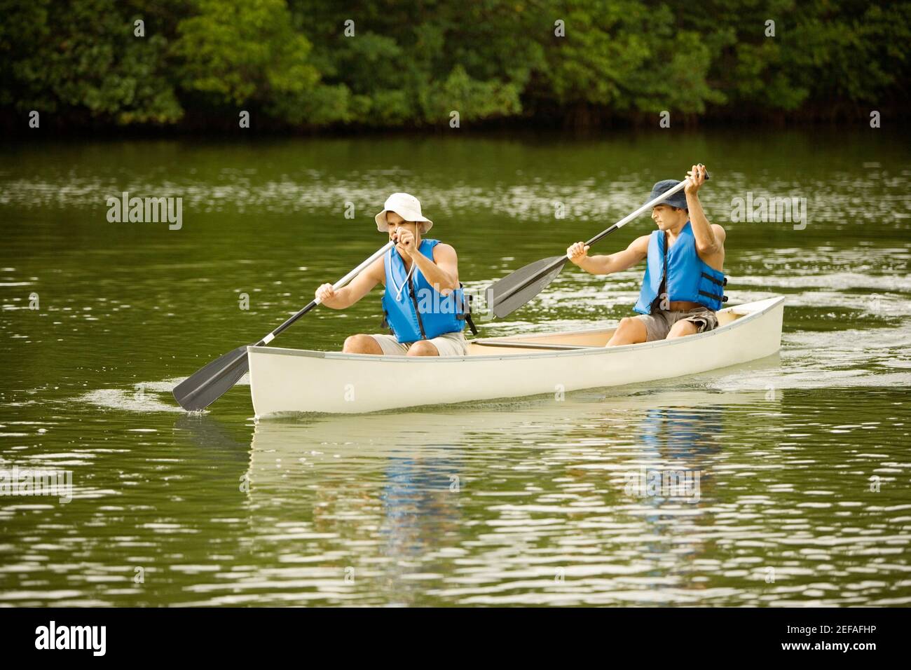 Zwei Männer mit mittlerem Erwachsenenalter, die in einem See Boot fahren Stockfoto