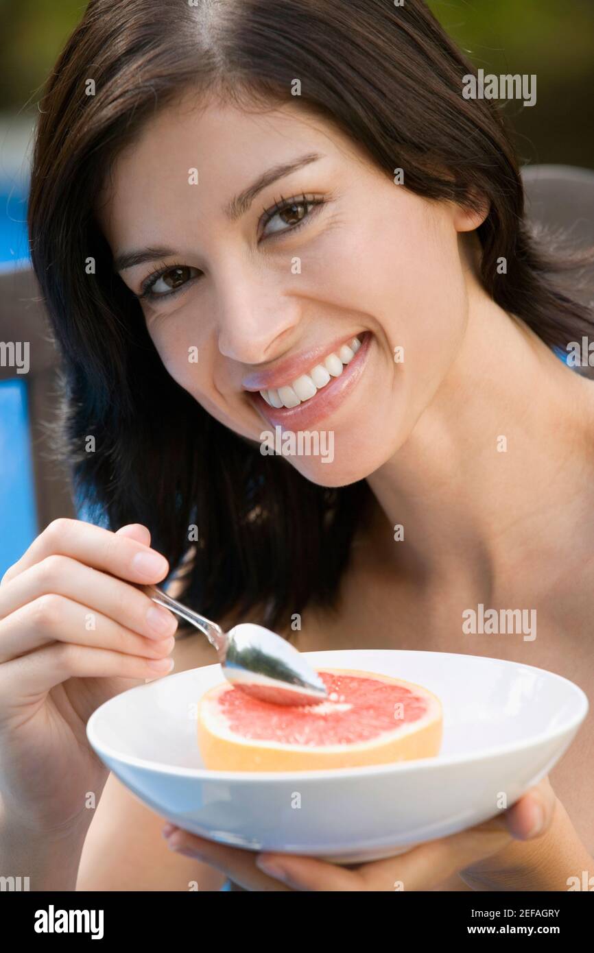 Porträt einer jungen Frau, die Grapefruit isst und lächelt Stockfoto