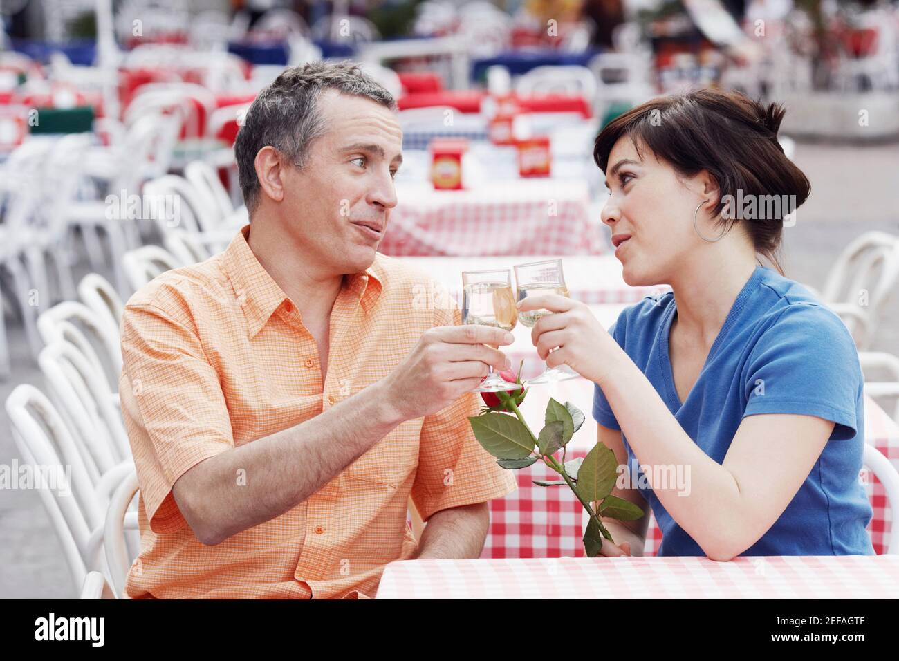 Reifer Mann und eine junge Frau, die auf einem Bürgersteig toasten Café Stockfoto