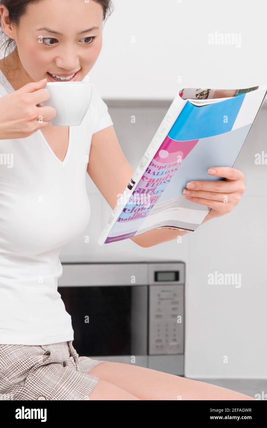 Seitenprofil einer jungen Frau, die Tee trinkt und liest Eine Zeitschrift Stockfoto