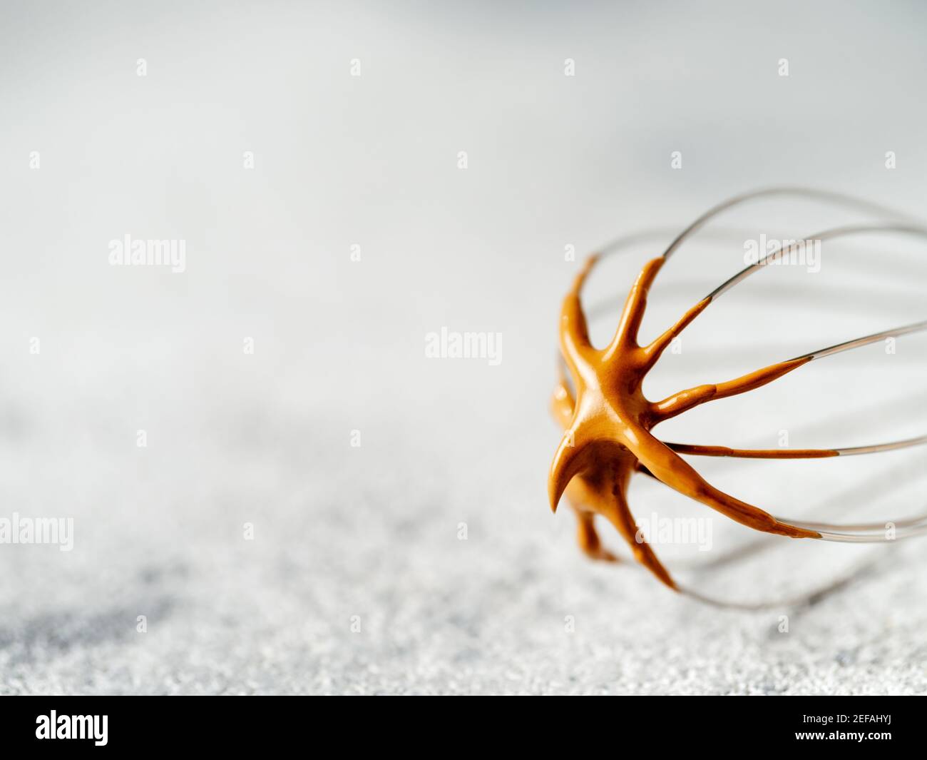 Schneebesen mit trendigem koreanischen Dalgona-Kaffee. Schlagsahne Instant-Kaffee auf Metall Schneebesen über grauen Zement Hintergrund mit Kopierraum für Text oder Design Stockfoto