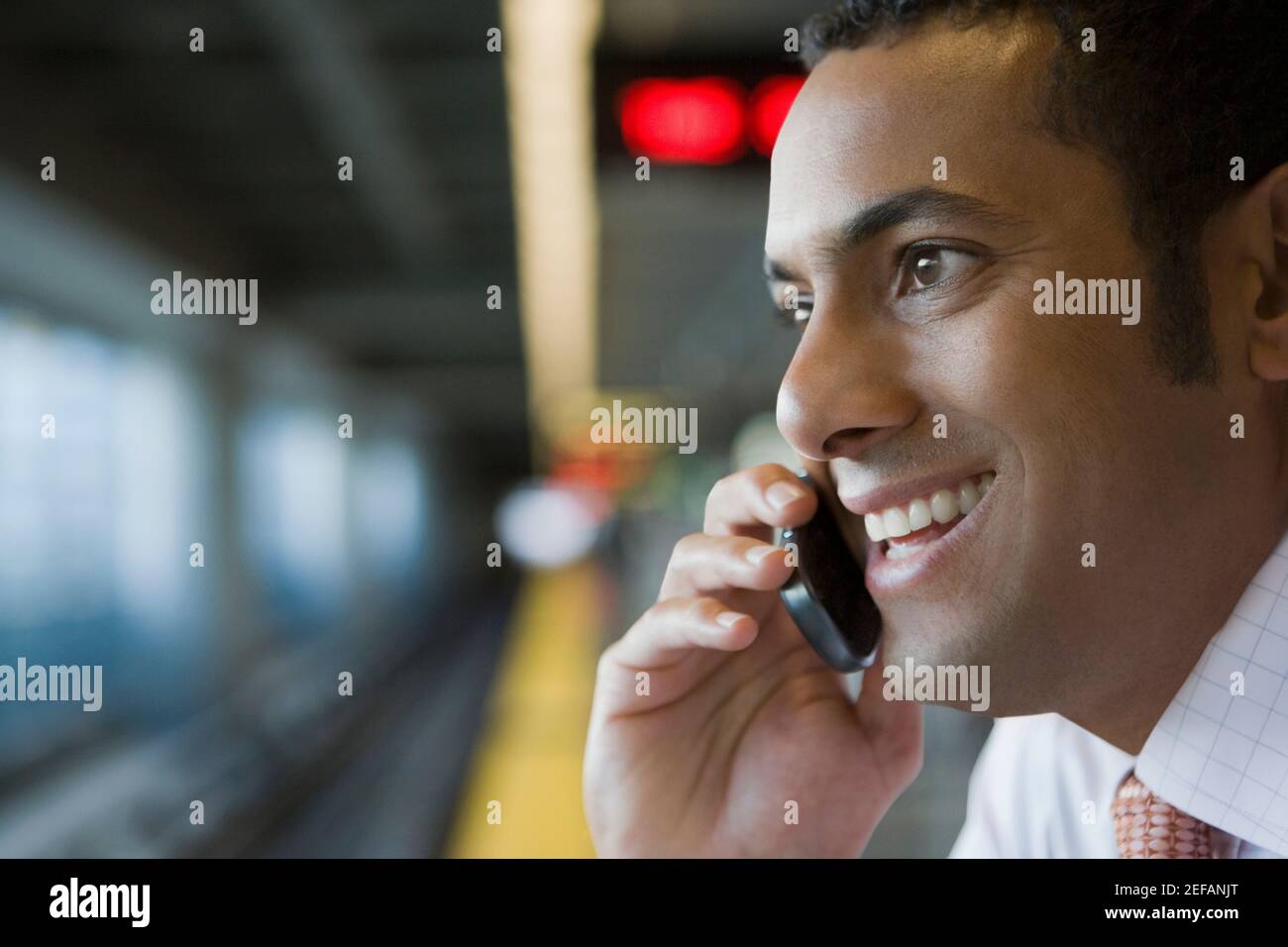 Nahaufnahme eines Geschäftsmannes, der mit einem Mobiltelefon spricht Eine U-Bahn-Station Stockfoto