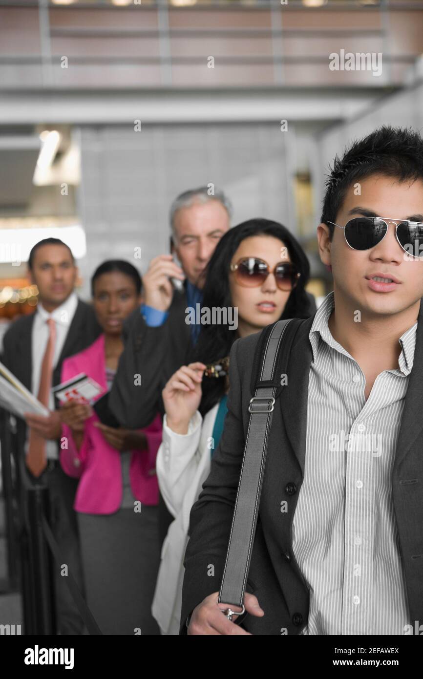 Fünf Führungskräfte, die in einer Reihe an einem Flughafen stehen Stockfoto