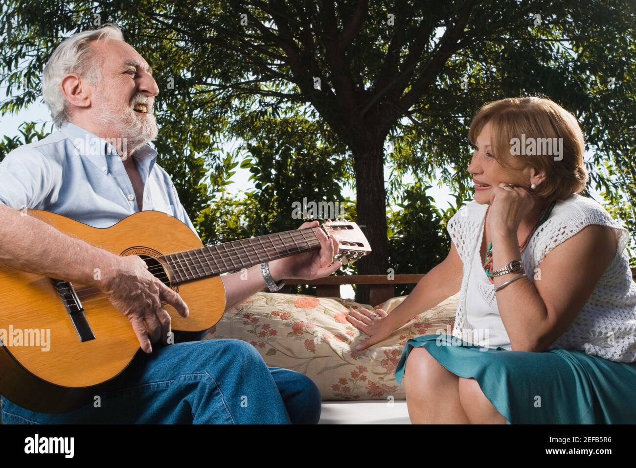 Älterer Mann spielt Gitarre vor einem Senioren Frau Stockfoto