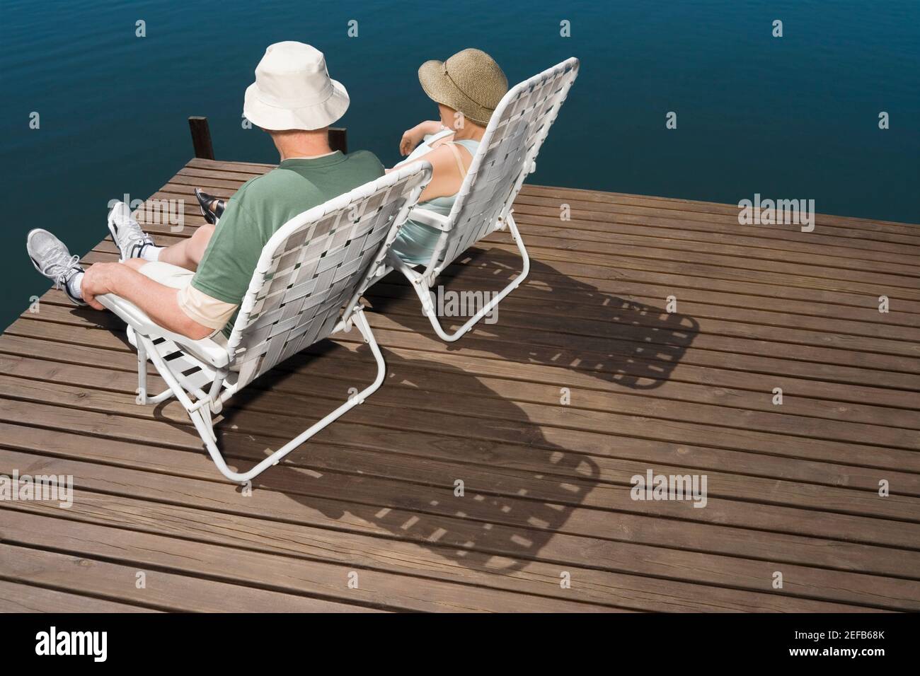 Rückansicht eines älteren Ehepaares, das auf Stühlen sitzt Das Seeufer Stockfoto