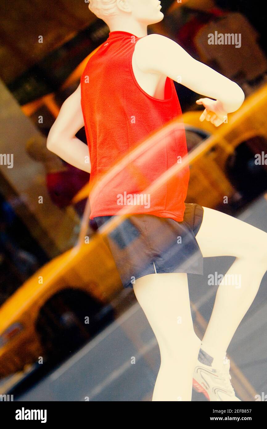 Schaufensterpuppe hinter dem Glas eines Bekleidungsladens und Reflexion Von einem Auto darauf Stockfoto