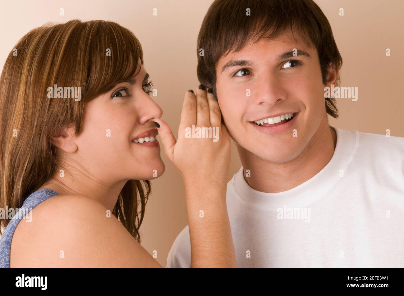 Junge Frau mit einem jungen Mann flüstert Stockfoto