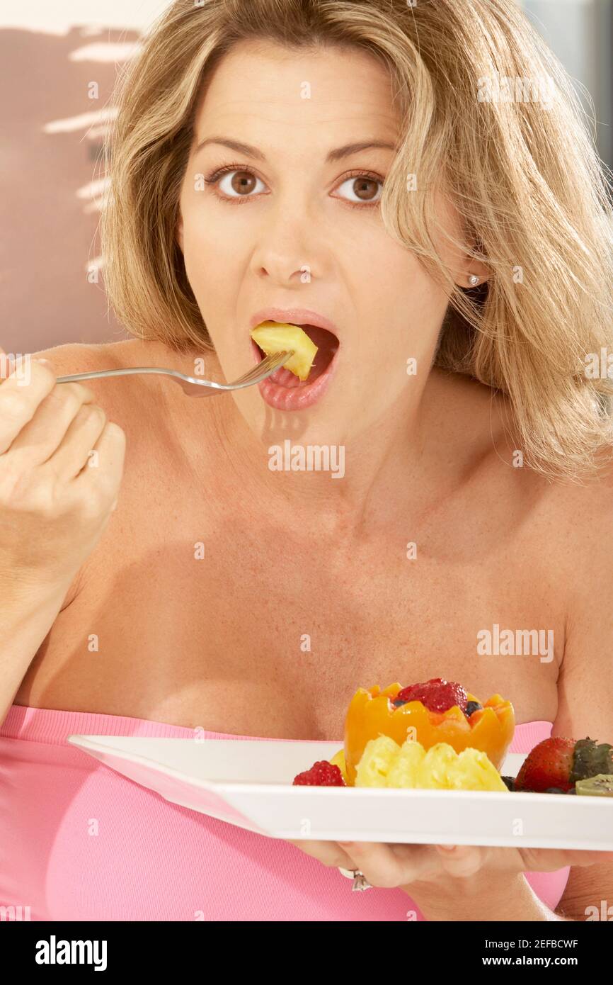 Porträt einer mittleren erwachsenen Frau, die eine Papaya isst Stockfoto