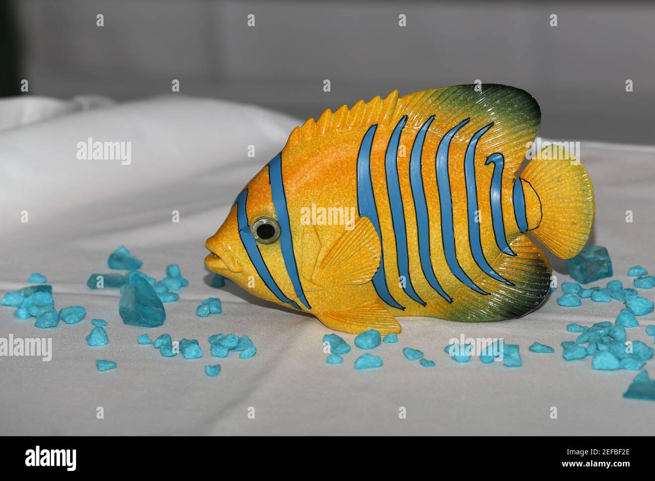 Nahaufnahme eines dekorativen Kunststoff-Falterfisches auf dem Tisch mit Blaue Felsen darauf Stockfoto