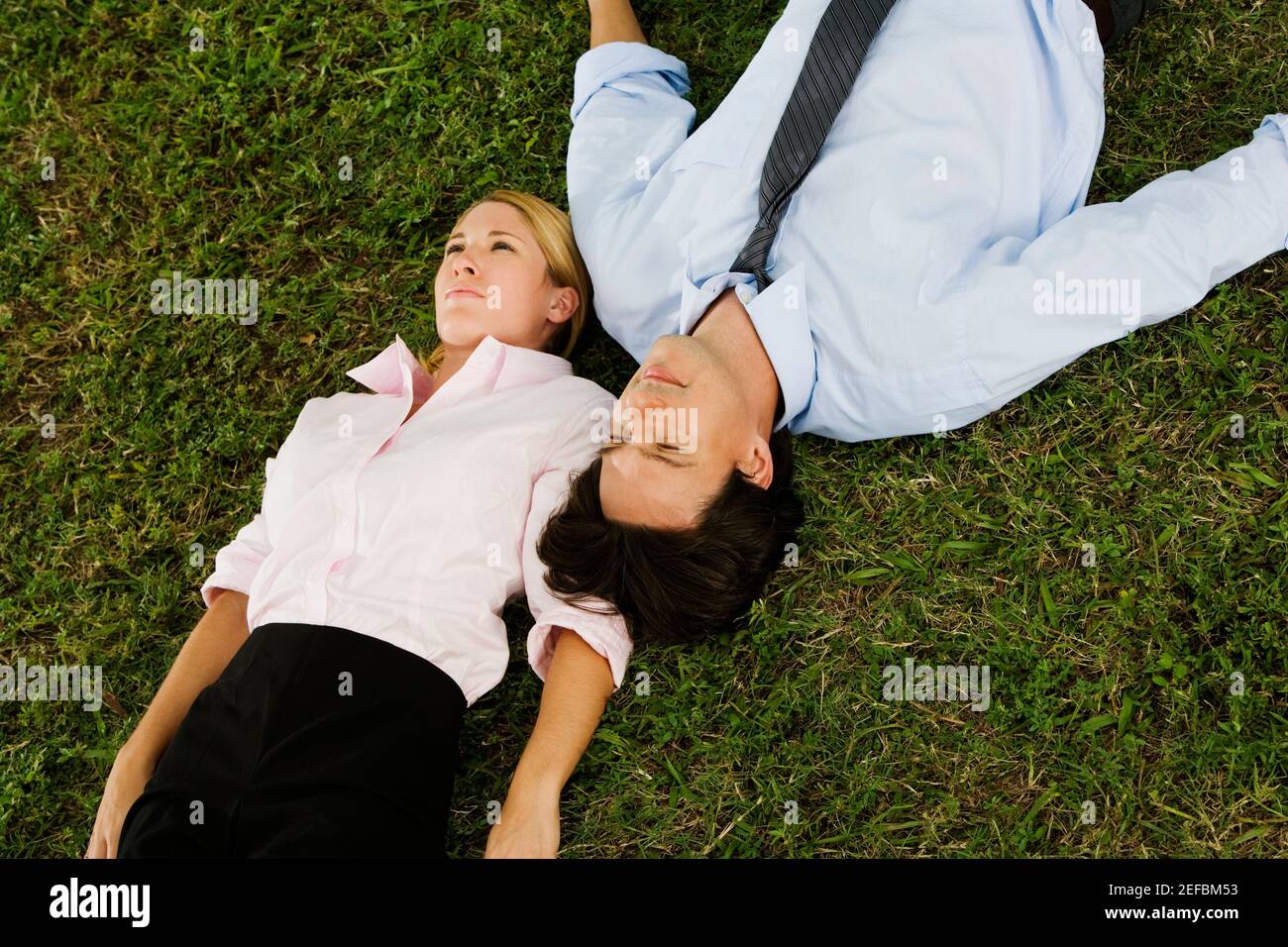 Aus der Sicht einer Geschäftsfrau und eines Geschäftsmannes lügen Auf dem Gras Stockfoto