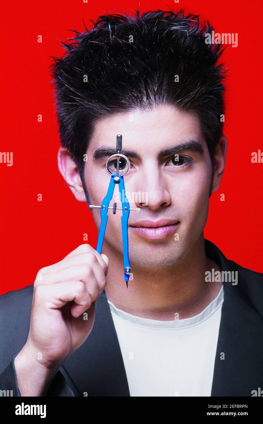 Porträt eines jungen Mannes, der einen Zeichenkompass in der Hand hält Vor seinem Auge Stockfoto