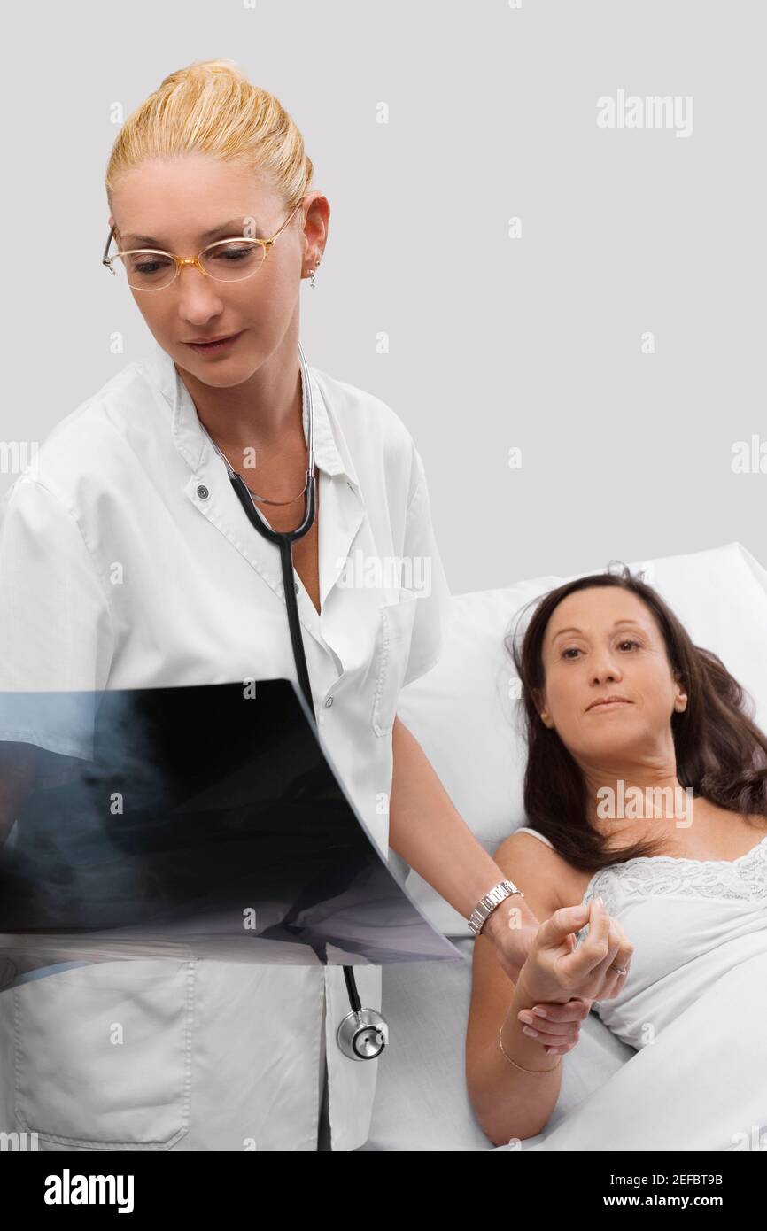 Ärztin, die Hand eines Patienten hält und anschaut Ein Röntgenbericht Stockfoto
