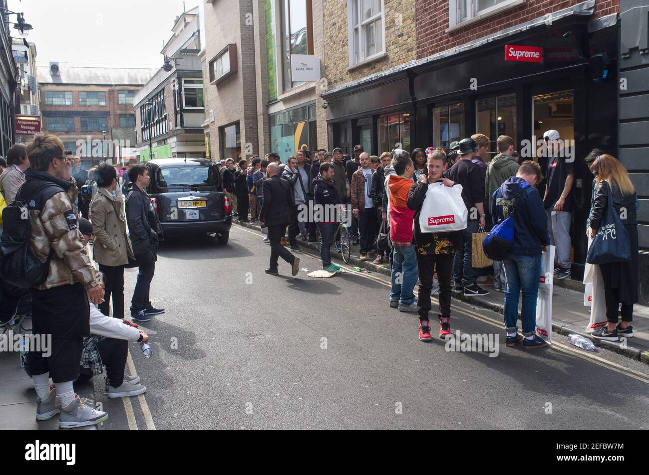 Eine Schlange vor dem kultigen Skateboard-Bekleidungsgeschäft Supreme, Peter Street, Soho, London, Großbritannien. 24 April 2014 Stockfoto