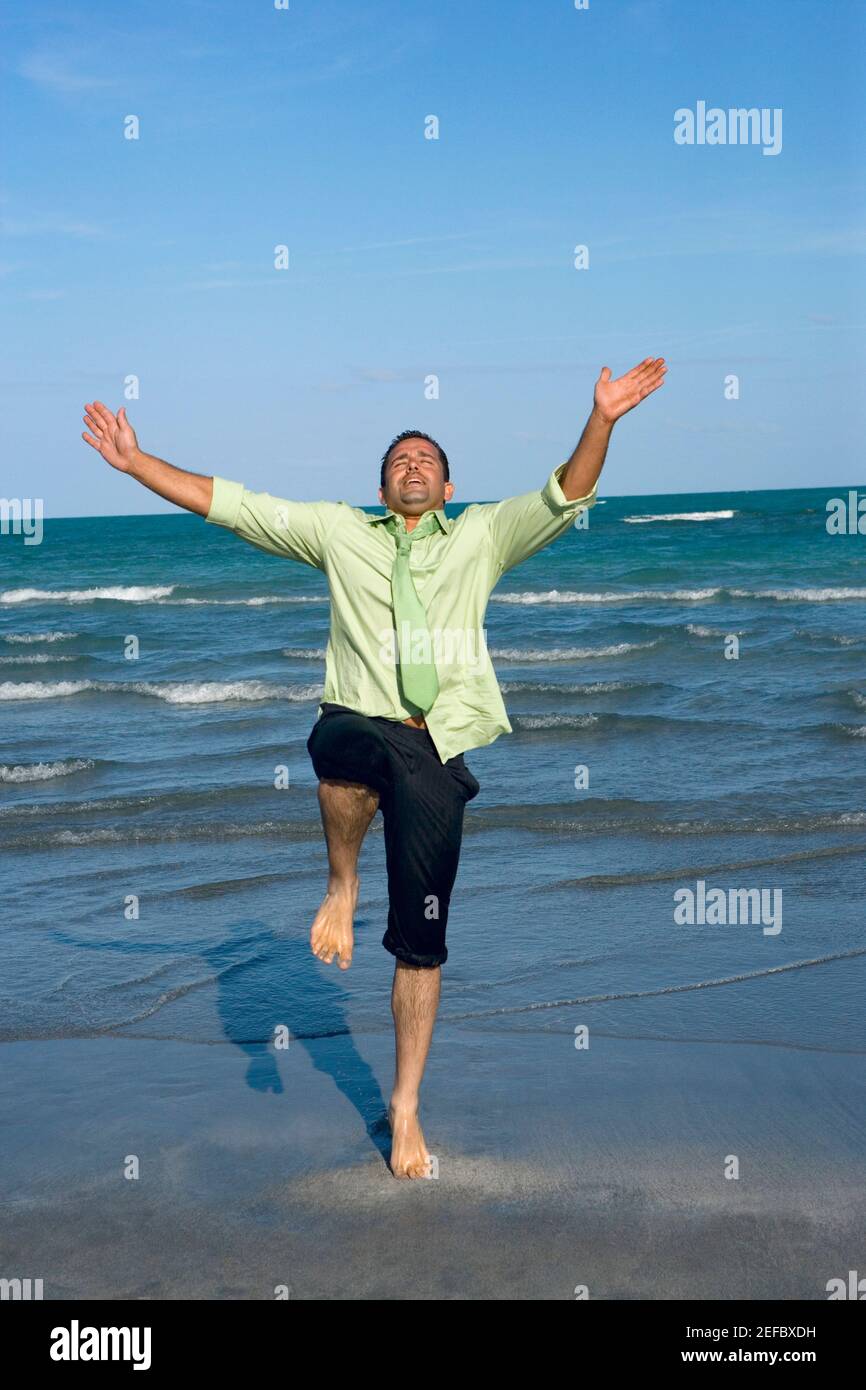 Mittelerwachsener Mann, der auf seinem Bein auf dem steht Strand Stockfoto