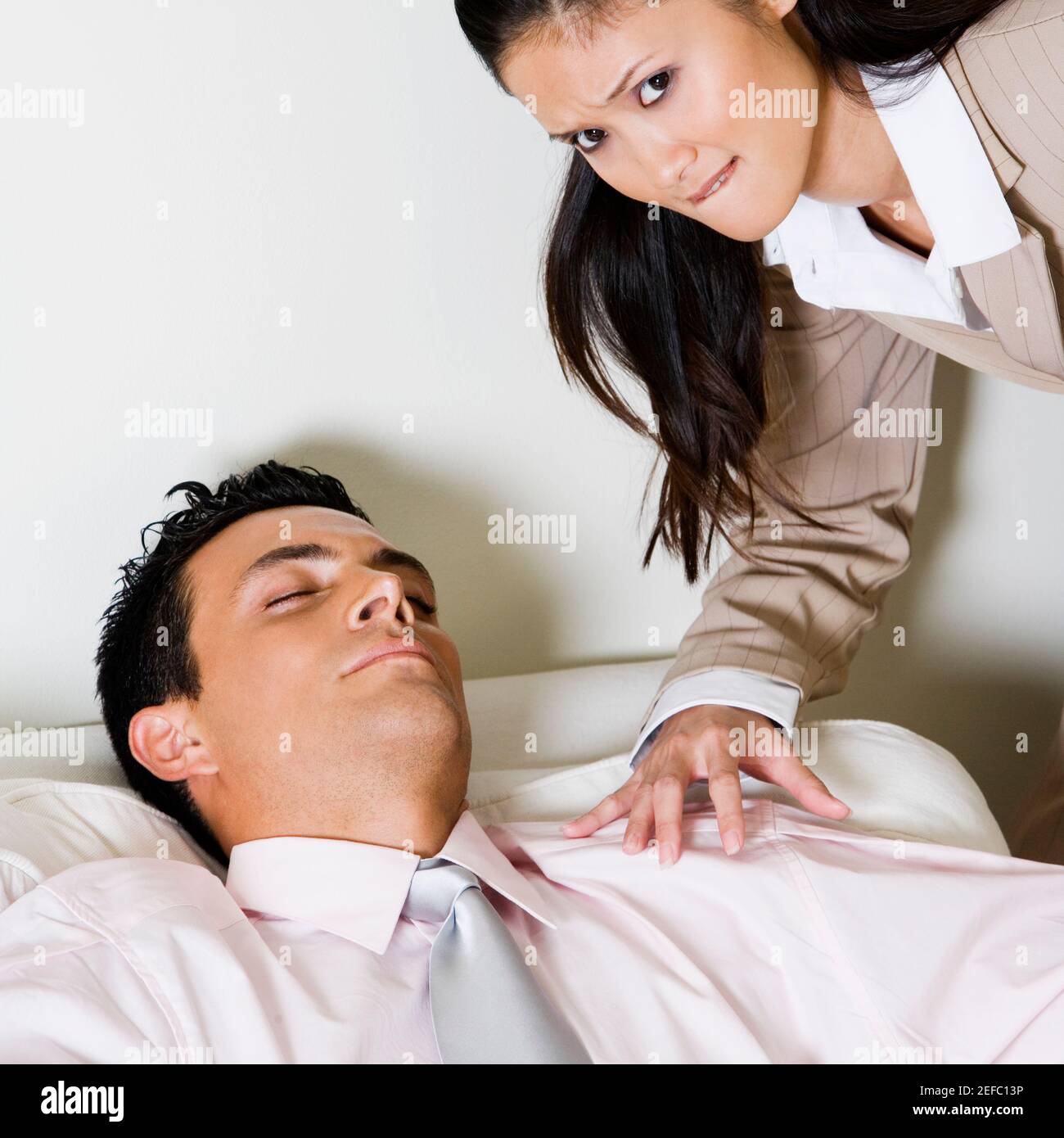 Porträt einer Geschäftsfrau, die sich über einen Geschäftsmann beugt, auf dem er sitzt Ein Sofa Stockfoto