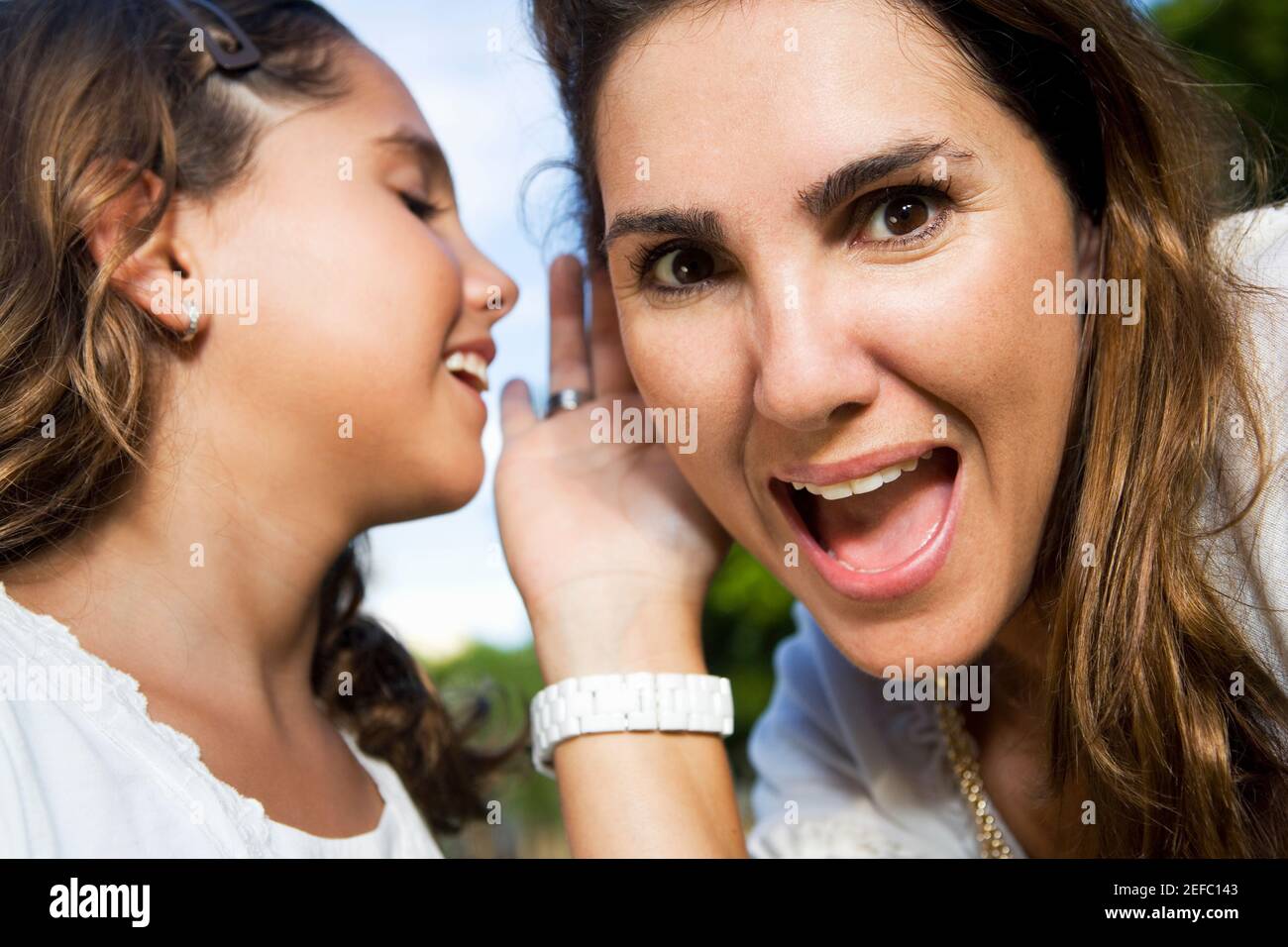 Nahaufnahme eines Mädchens, das motherÅ½s ihr Ohr flüstert Stockfoto