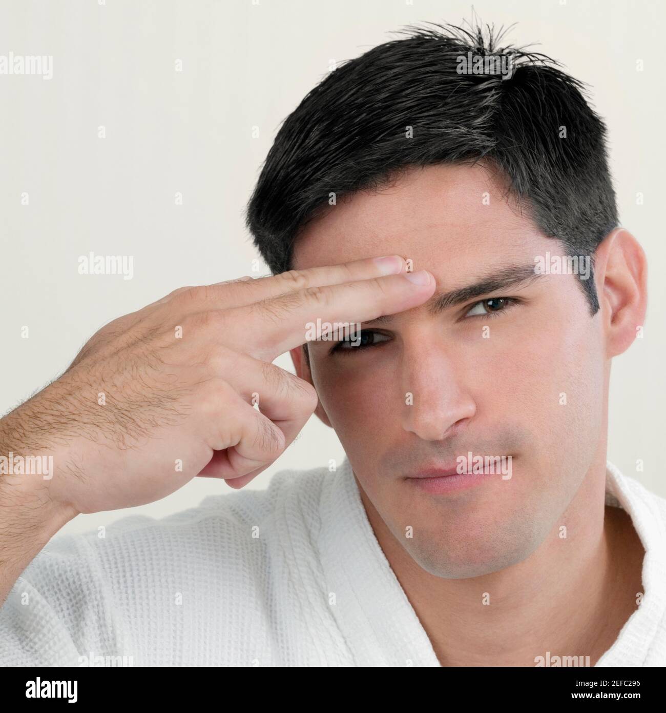 Porträt eines jungen Mannes, der ein Waffenschild schließt Zu seinem Tempel Stockfoto