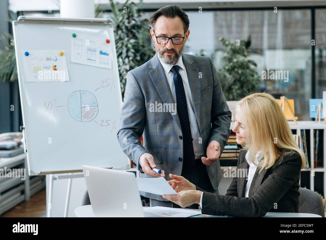 Fokussierte Geschäftspartner, die an Unternehmensprojekten arbeiten und einen neuen Plan besprechen. Stilvolle blonde-Haar Frau fragen Sie um Rat über einige Dokumente oder finanzielle Grafiken von confidenr männlichen Kollegen Stockfoto