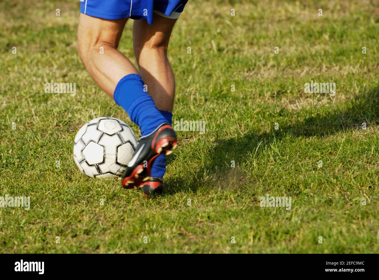 Low-Section-Ansicht eines Fußballspielers Ausweichen eines Fußballs Ball Stockfoto
