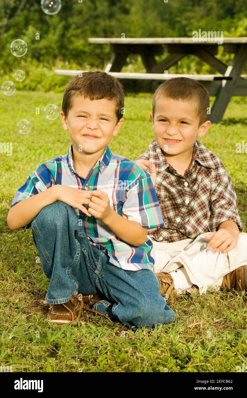 Nahaufnahme von zwei Jungen, die lächelnd im Garten sitzen Stockfoto