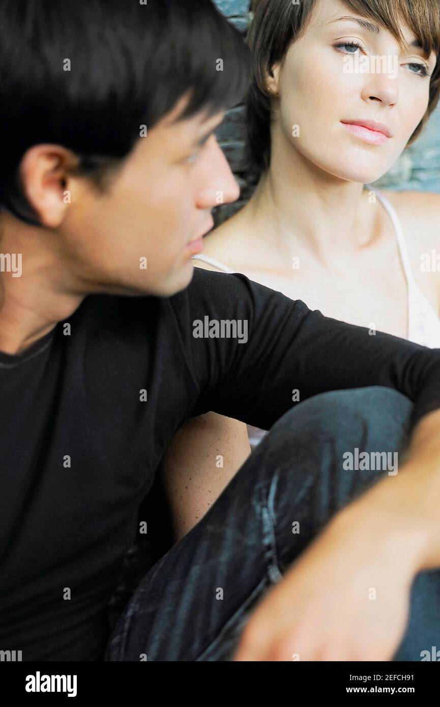 Zwei junge Männer, die mit einer jungen Frau sitzen Stockfoto