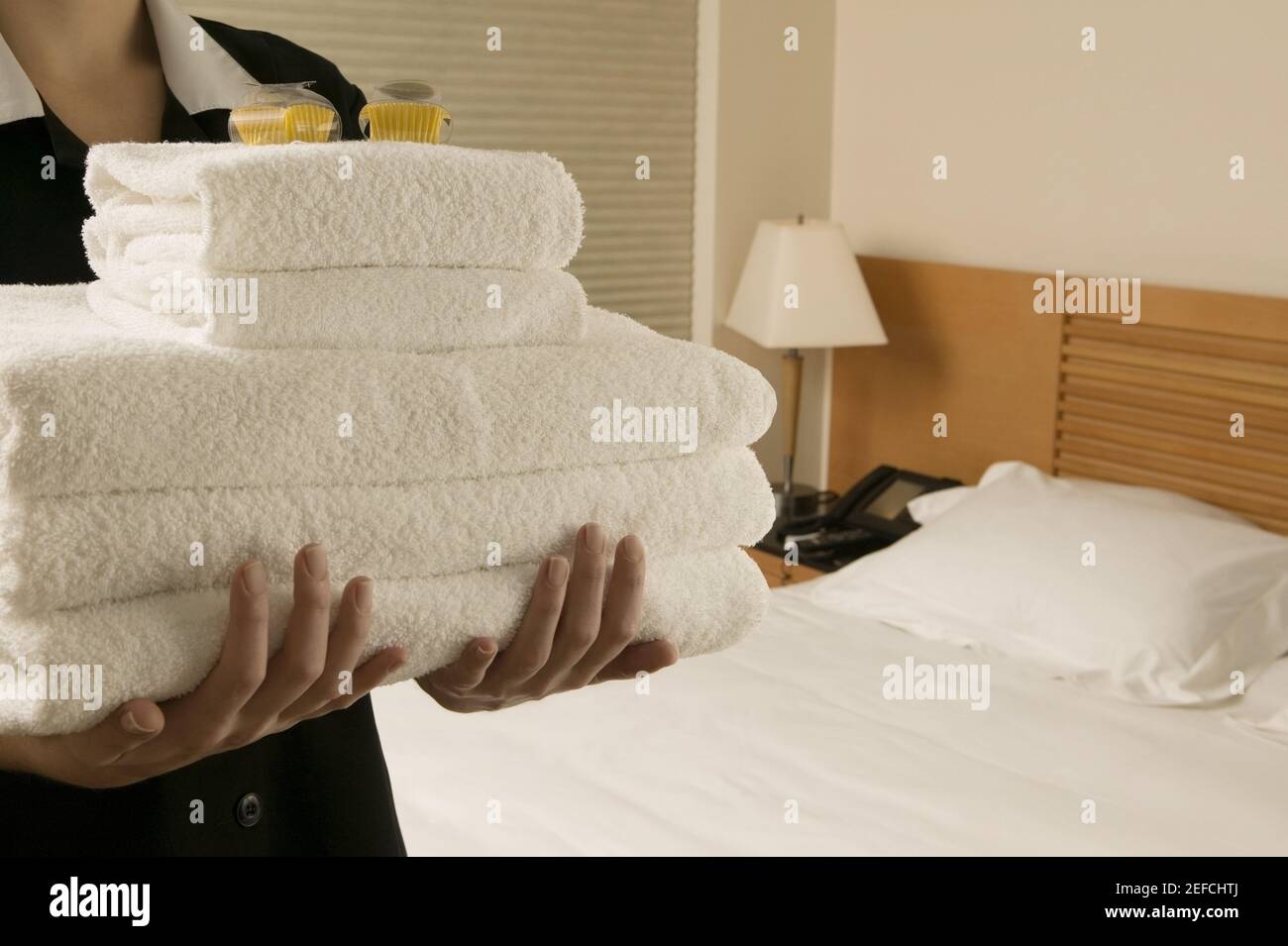 Mittlere Ansicht einer Kellnerin mit einem Stapel Handtücher Stockfoto
