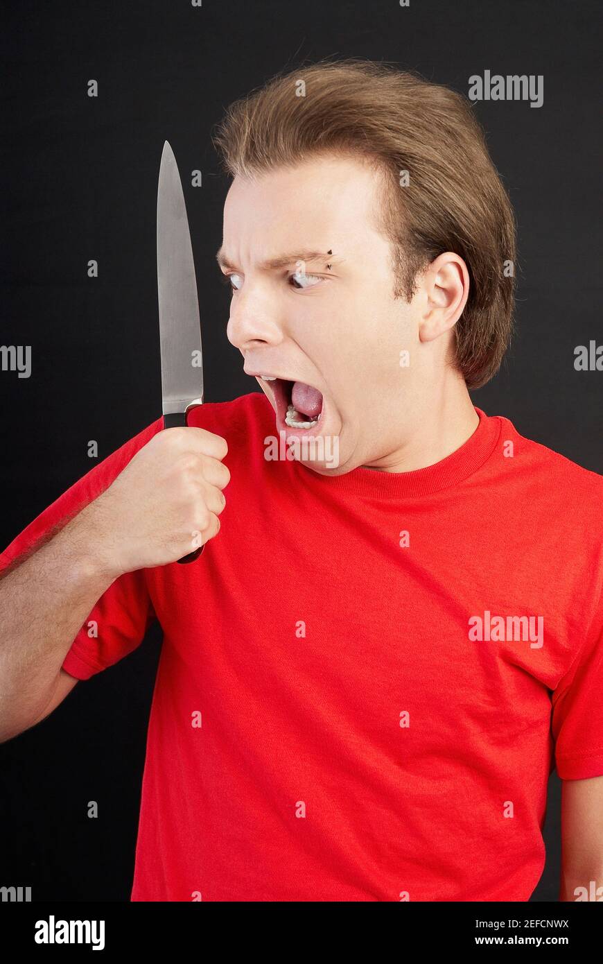 Nahaufnahme eines jungen Mannes, der ein Messer hält und schaut Angst Stockfoto