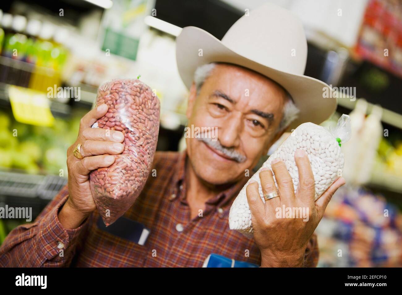 Porträt eines älteren Mannes, der Pakete in einem Supermarkt hält Stockfoto