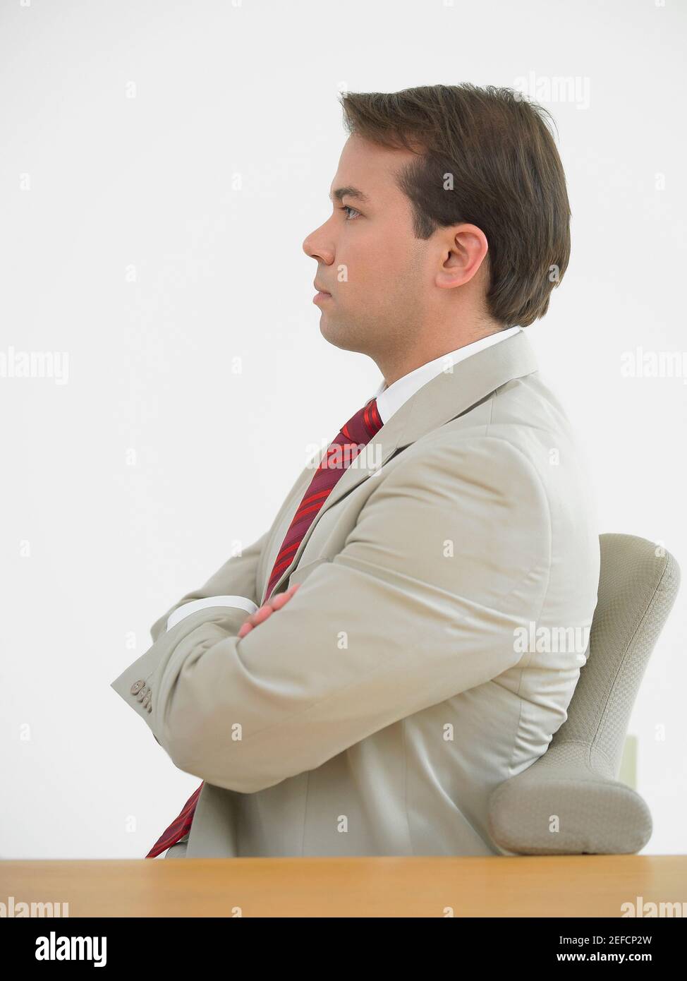 Seitenprofil eines Geschäftsmannes, der mit gekreuzten Armen sitzt Stockfoto