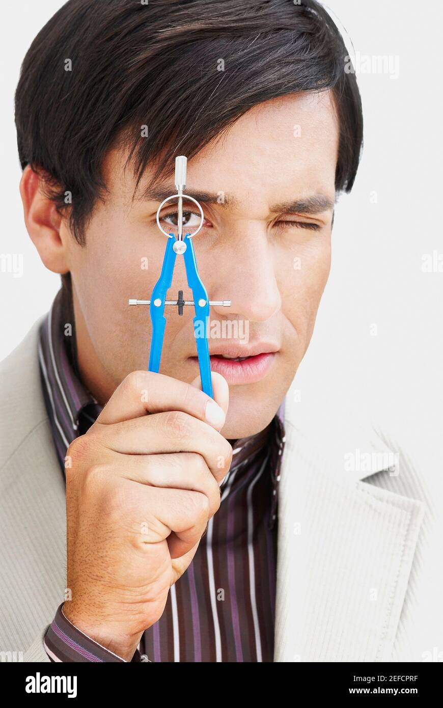 Porträt eines jungen Mannes, der einen Zeichenkompass in der Hand hält Vor seinem Auge Stockfoto