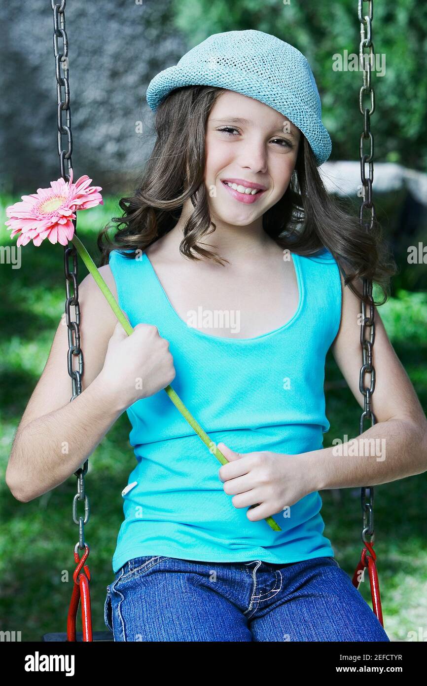 Portrait eines Mädchens, das eine Blume hält und darauf sitzt Eine Kettenschwinge Stockfoto