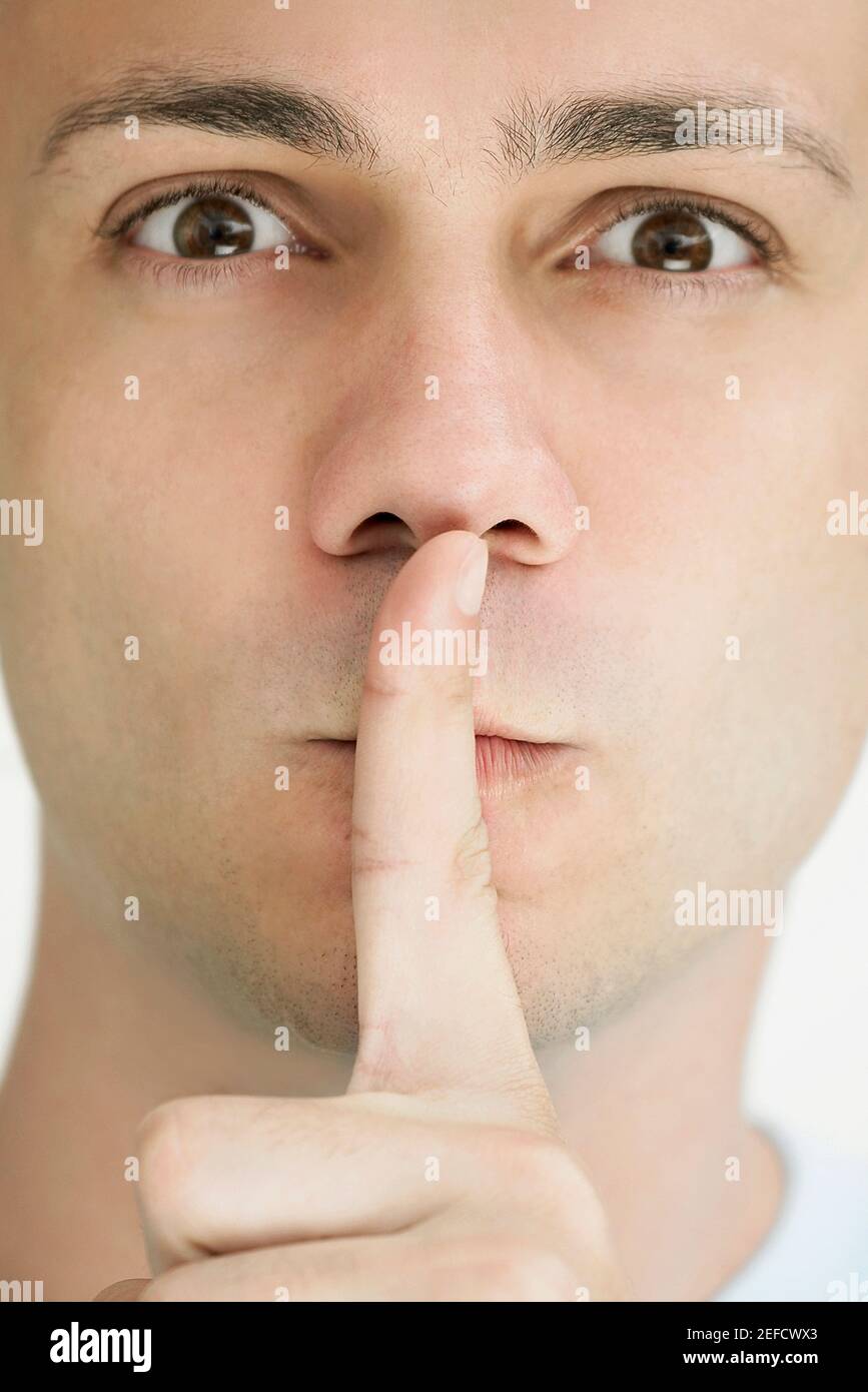 Porträt eines jungen Mannes mit seinem Finger auf seine Lippen Stockfoto